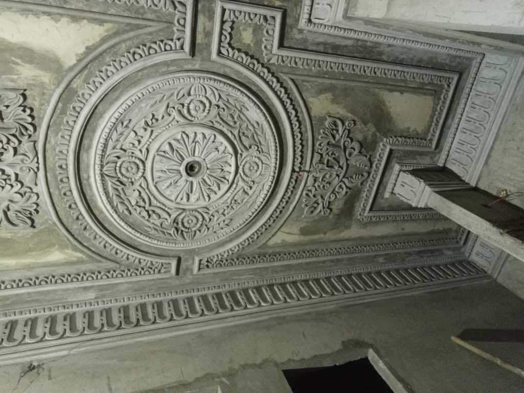 Circular plaster ceiling medallion with floral relief, still unpainted.