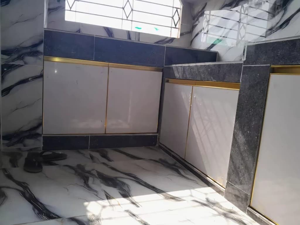Corner kitchen with white doors, a gold rail, and a dark granite worktop under a marble wall.
